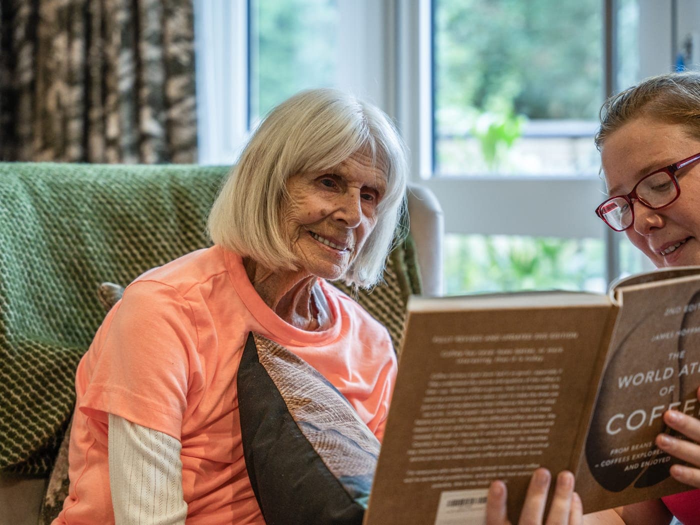 A resident and a carer reading together at Cedar Lodge